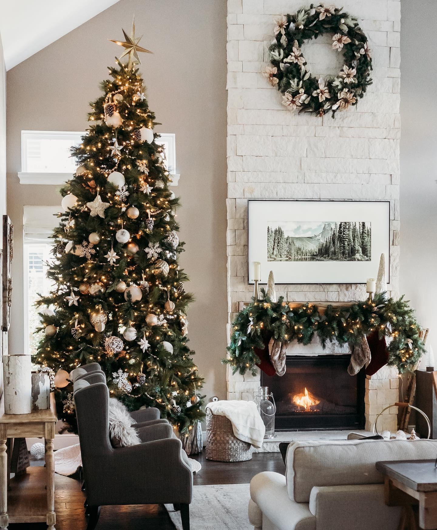 Spacious living room with a two-story ceiling, a grand Christmas tree, and a white stacked stone fireplace.