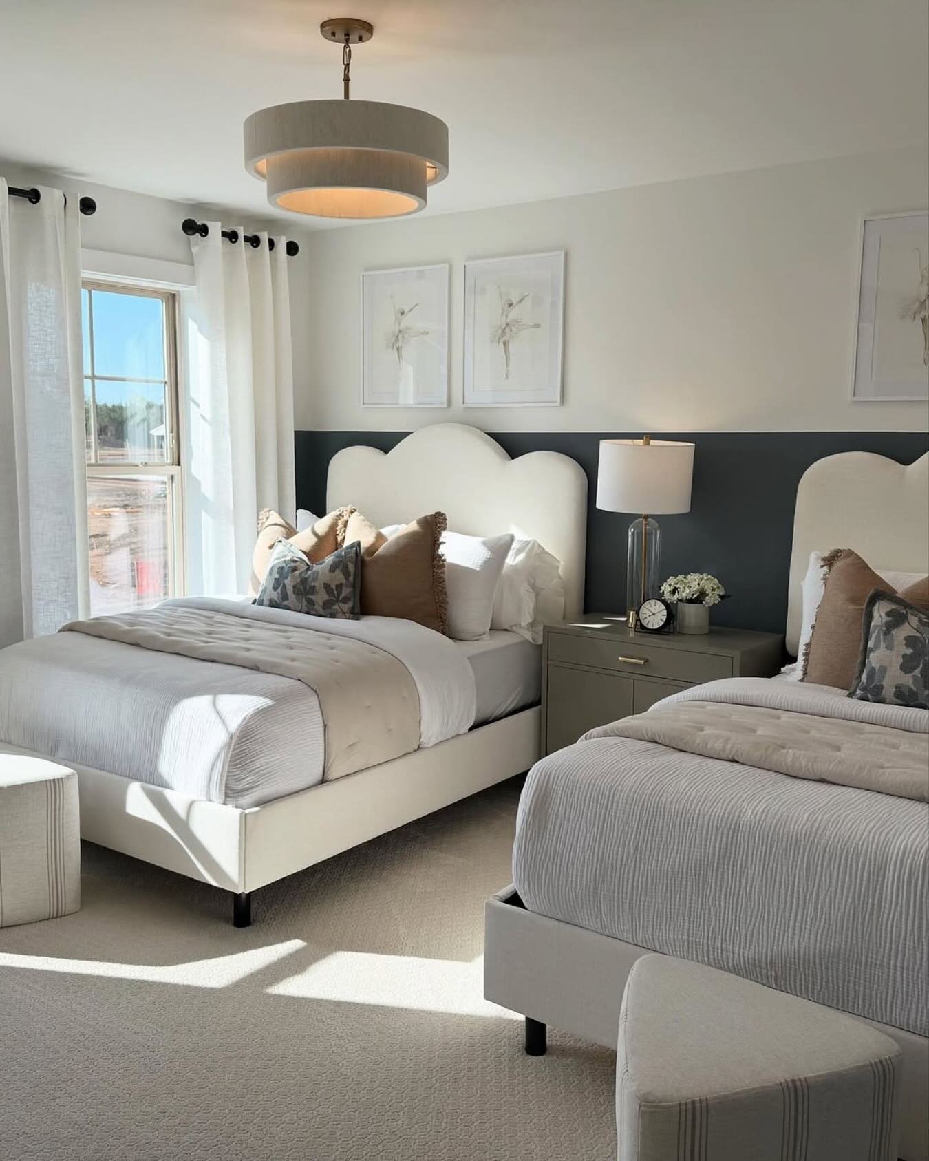 A modern twin bedroom with two beds, each having a white cloud-shaped headboard, against a two-toned gray and white wall.