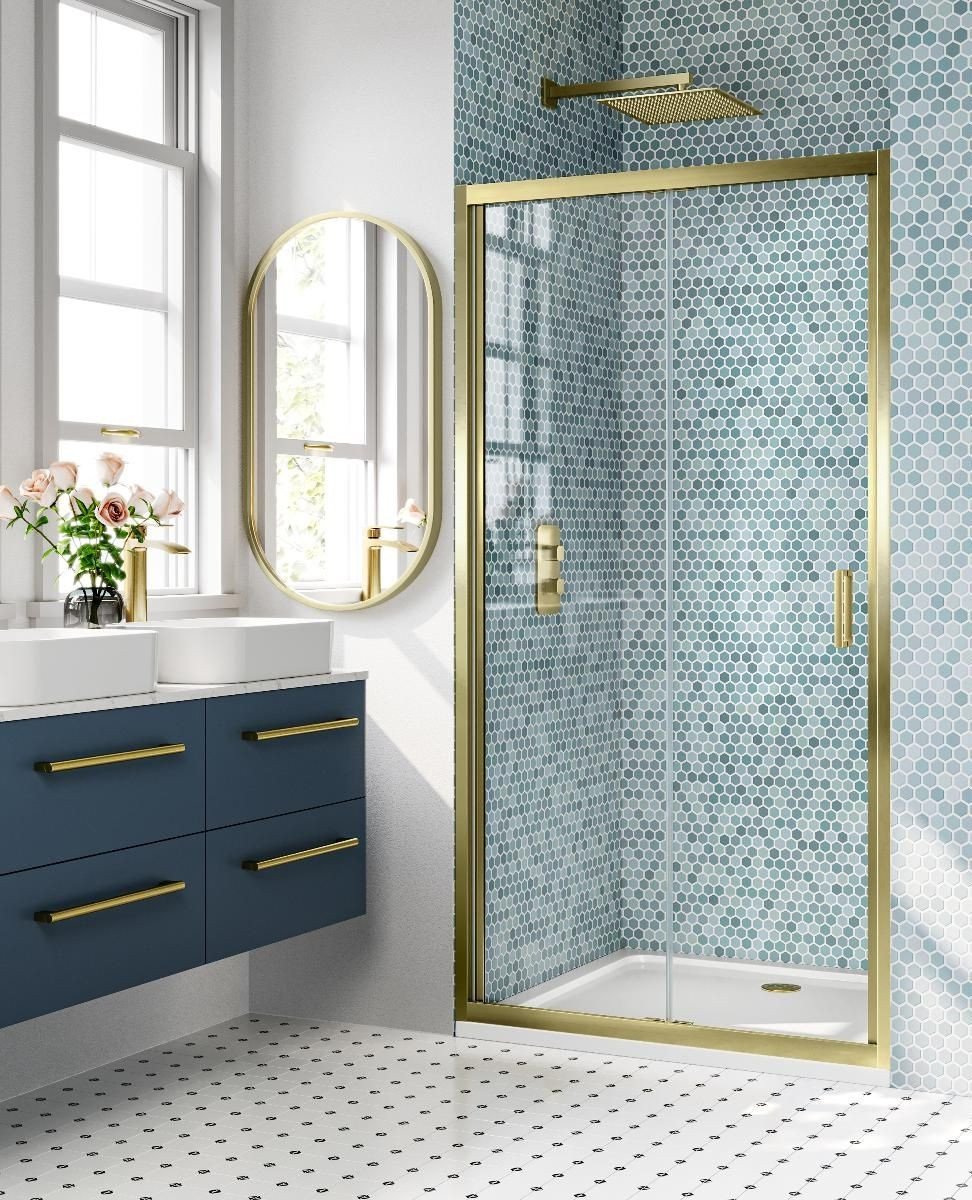 A bright bathroom featuring a walk-in shower with aqua and teal hexagonal mosaic tiles, framed in polished brass with matching fixtures.