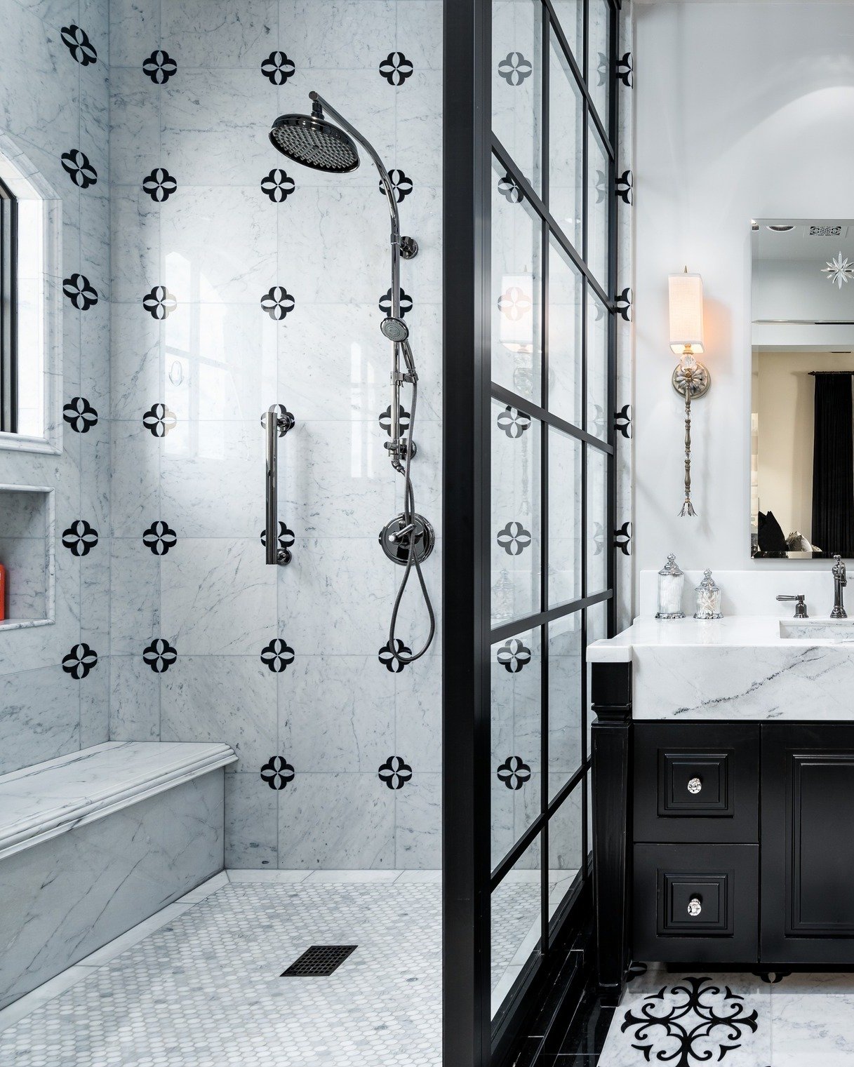A luxurious black and white shower featuring marble walls with black accent patterns, a built-in bench, and a black grid-style glass enclosure.