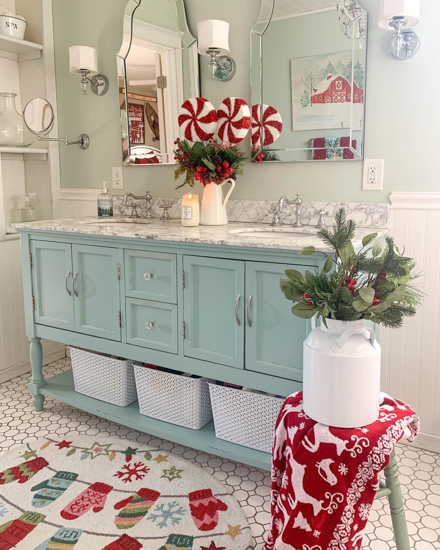 A mint green double vanity in a Christmas bathroom with peppermint ornaments, a mitten rug, and a red reindeer towel.