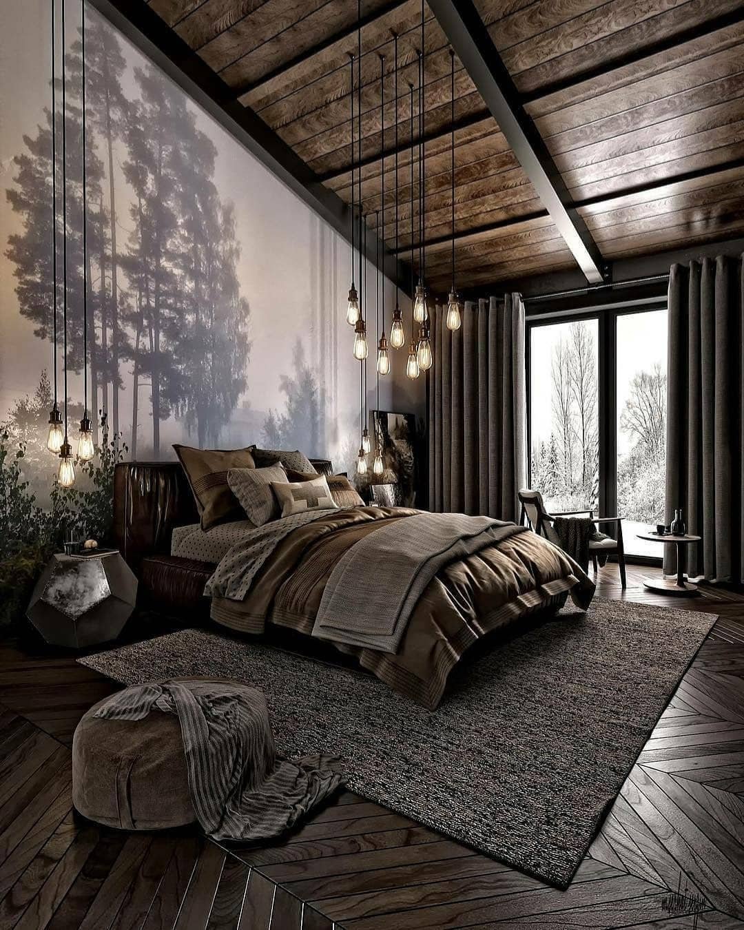 A rustic loft bedroom with a large forest mural on one wall, dark wood floors and ceiling, and a cluster of hanging Edison bulbs above a bed with layered brown and gray bedding.
