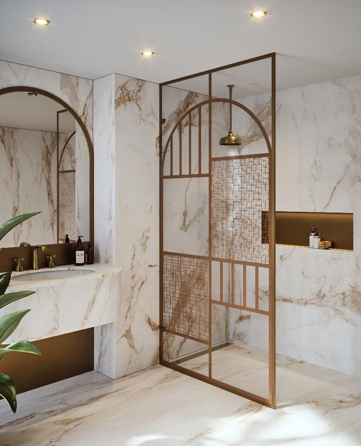 A luxury wet room featuring book-matched gold-veined marble and a striking copper-toned, metal-framed glass shower enclosure with Art Deco details.