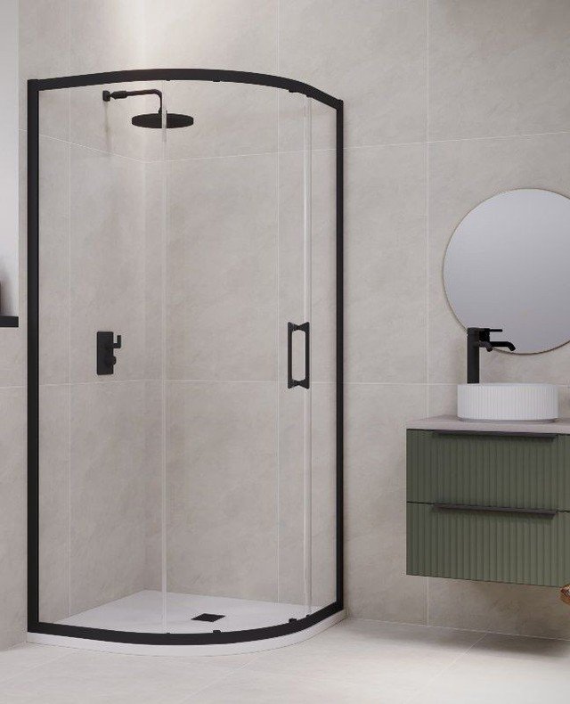 A small bathroom featuring a space-saving quadrant shower enclosure with a slim matte black frame and black fixtures against large beige wall tiles.