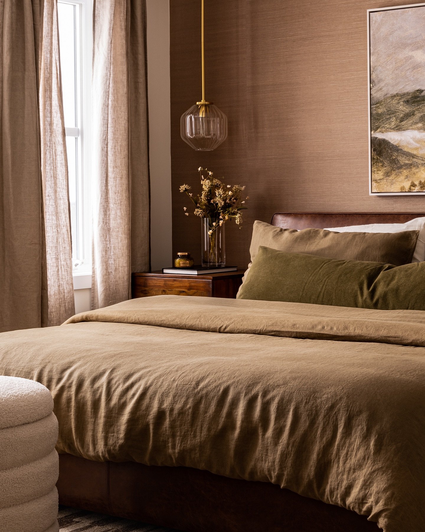 A modern bedroom with a globe-shaped glass pendant lamp hanging above a dark wooden nightstand.