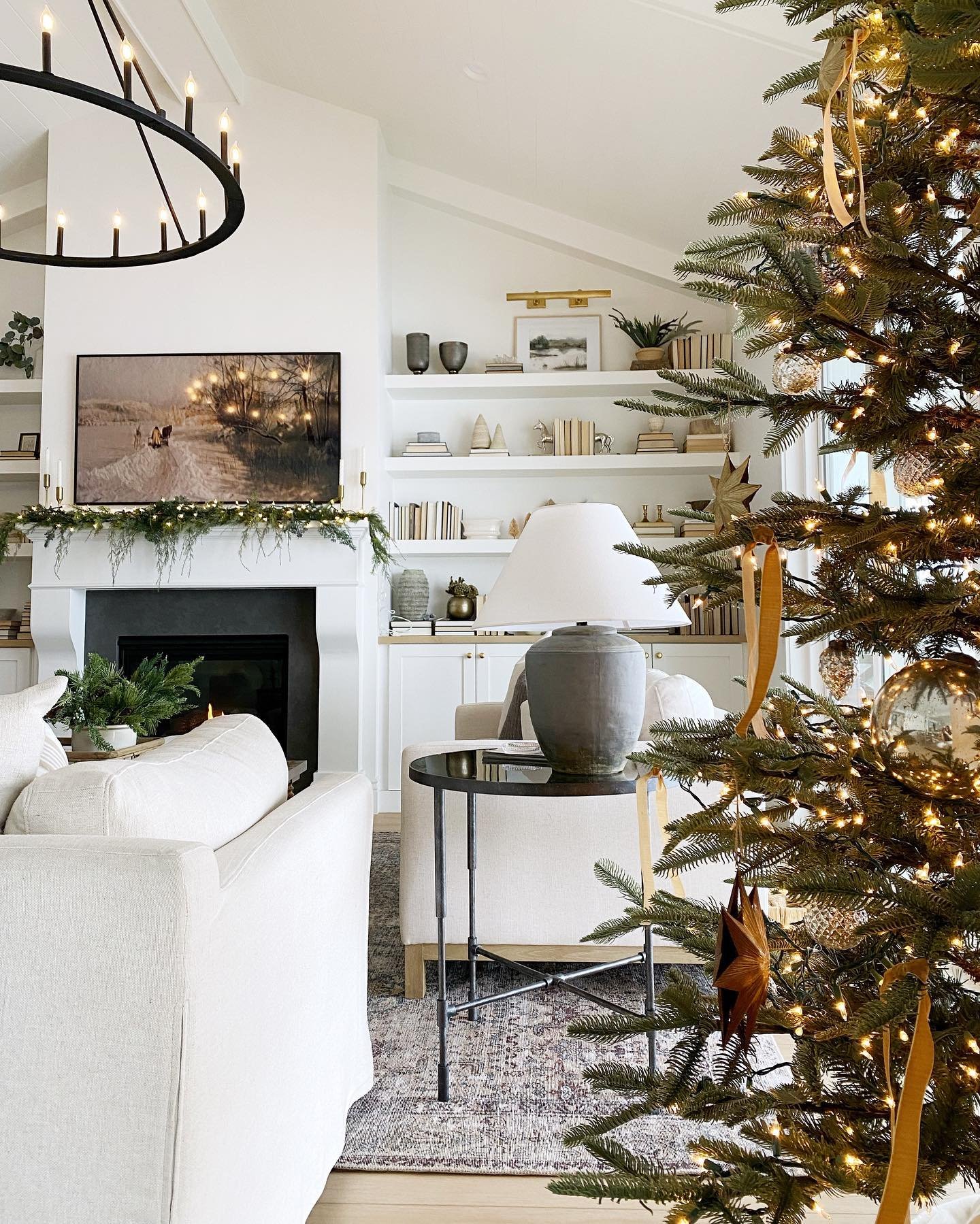 Contemporary living room with a white fireplace, black mantel, a large Christmas tree, and built-in shelving.