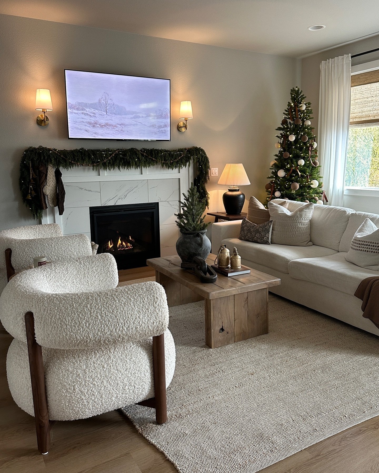 Cozy living room with a white slipcovered sofa, marble fireplace, and two curved boucle accent chairs.
