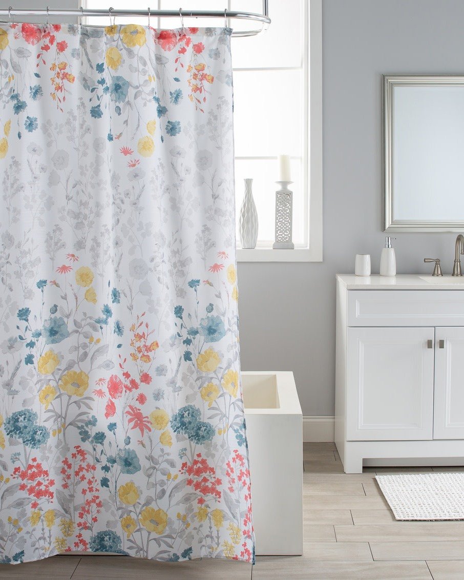 A white shower curtain with a repeating pattern of watercolor wildflowers in yellow, coral, and teal against a gray background.