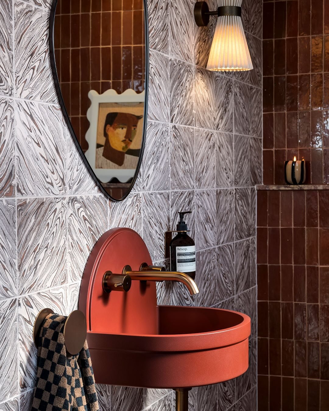 A small bathroom with a unique, red wall-mounted sink with a brass faucet.