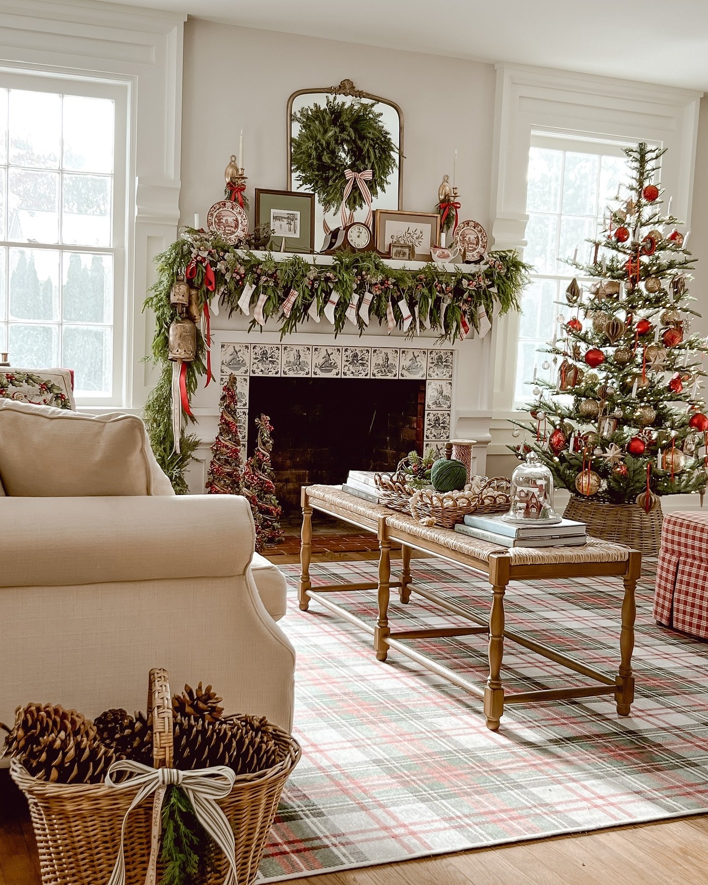 Cozy, classic living room with an ornate fireplace, a Christmas tree, and a red and green plaid area rug.