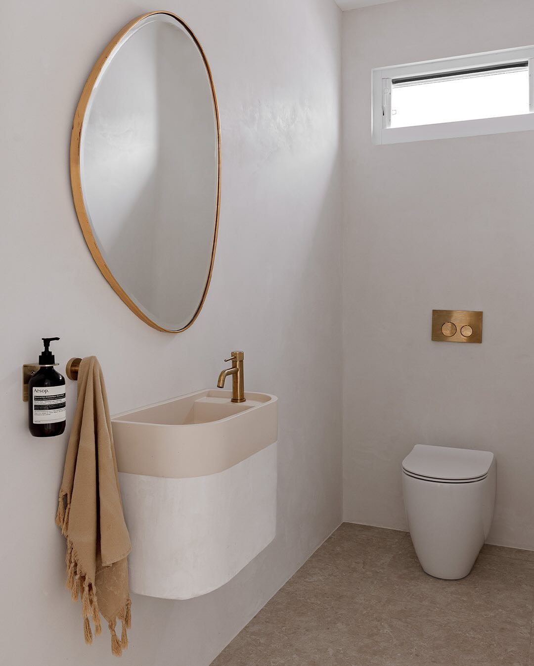 A small, minimalist bathroom with a two-tone wall-mounted sink in beige and white.