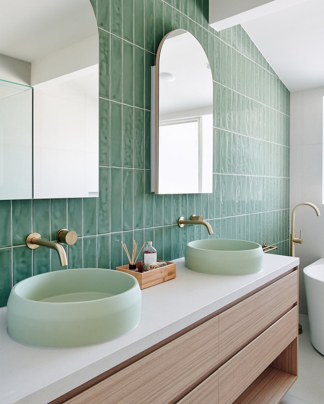 A double bathroom vanity with two pale green, round vessel sinks on a white countertop.