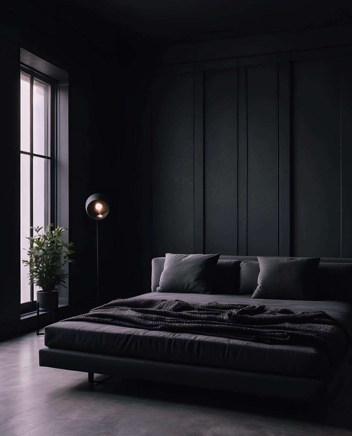 A minimalist black bedroom with vertical wall panels, a low-profile bed with dark grey bedding, and a large window with a plant.