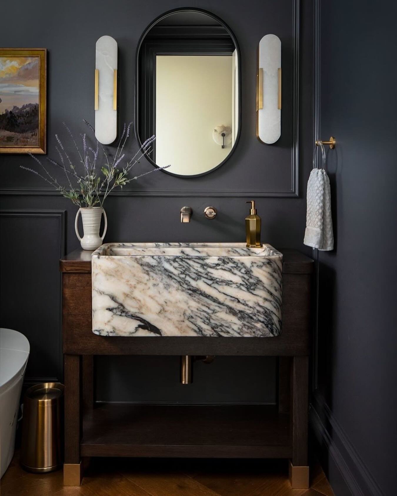 Powder room with dark charcoal walls, a wooden washstand, and a rectangular, veined marble vessel sink.