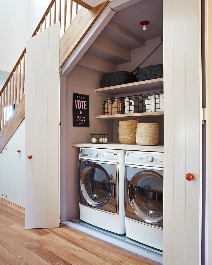 Stacked washer and dryer in a compact under-stairs closet with shelves.