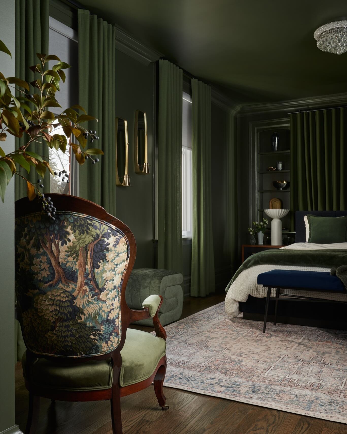 Luxurious dark green bedroom with velvet drapes and a patterned antique armchair.