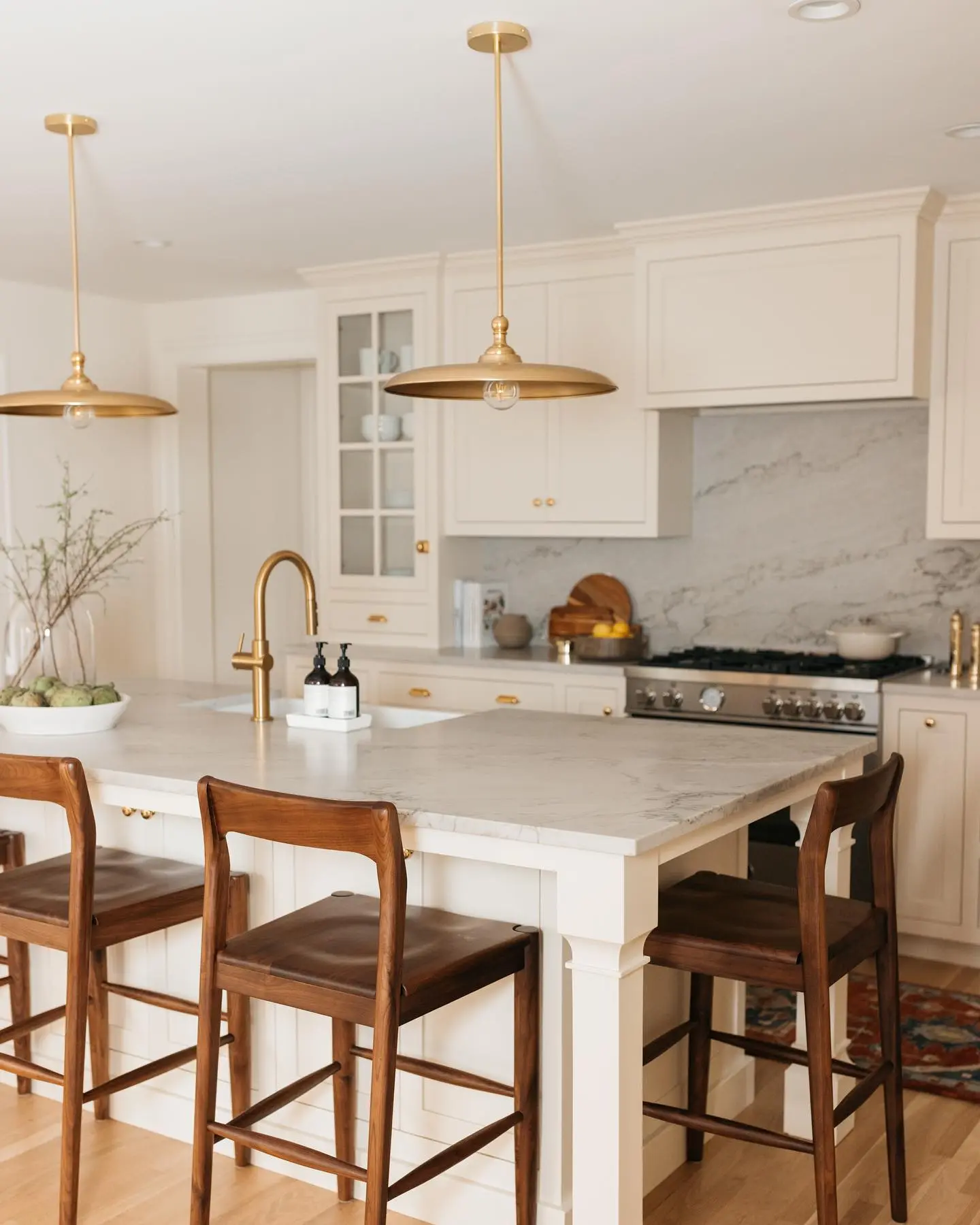Pair of simple white globe pendant lights over a sleek wood kitchen island.