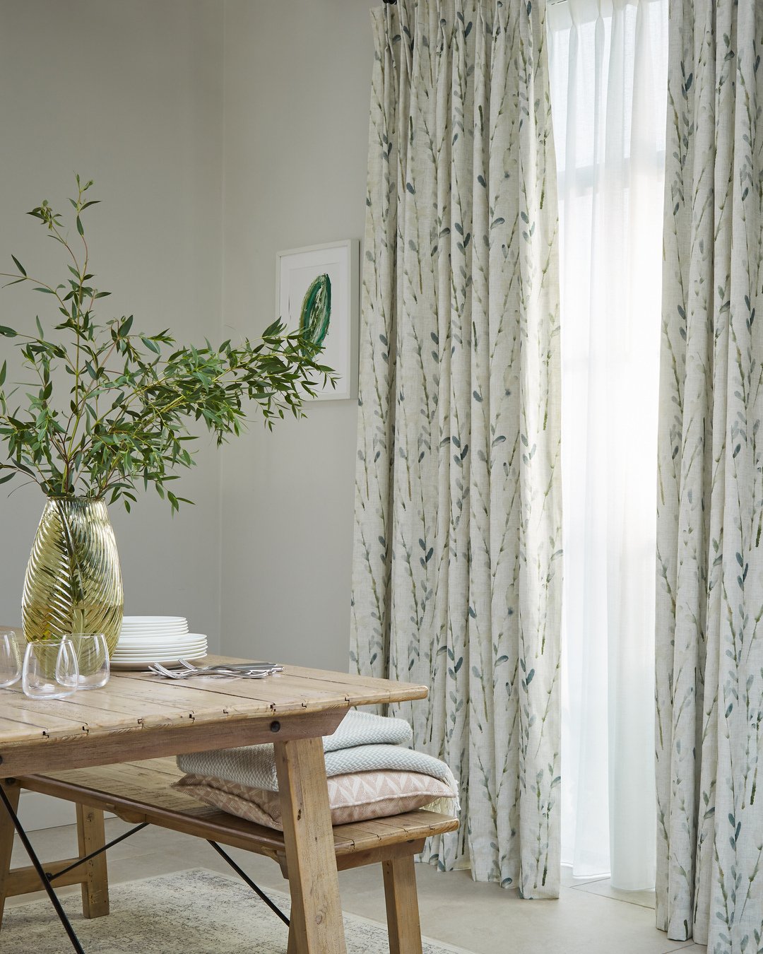 White curtains with a green botanical leaf print layered over white sheers.