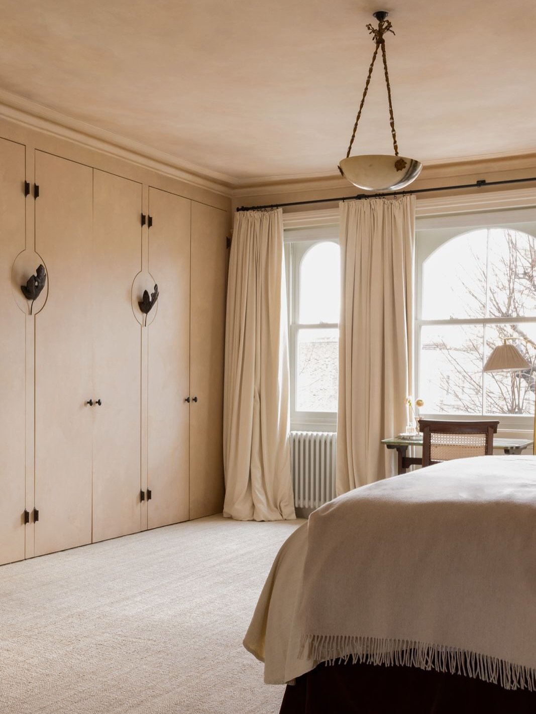 Flat-panel built-in wardrobe in a matte beige finish, featuring unique, artistic black metal sculptural door handles and matching smaller knobs.