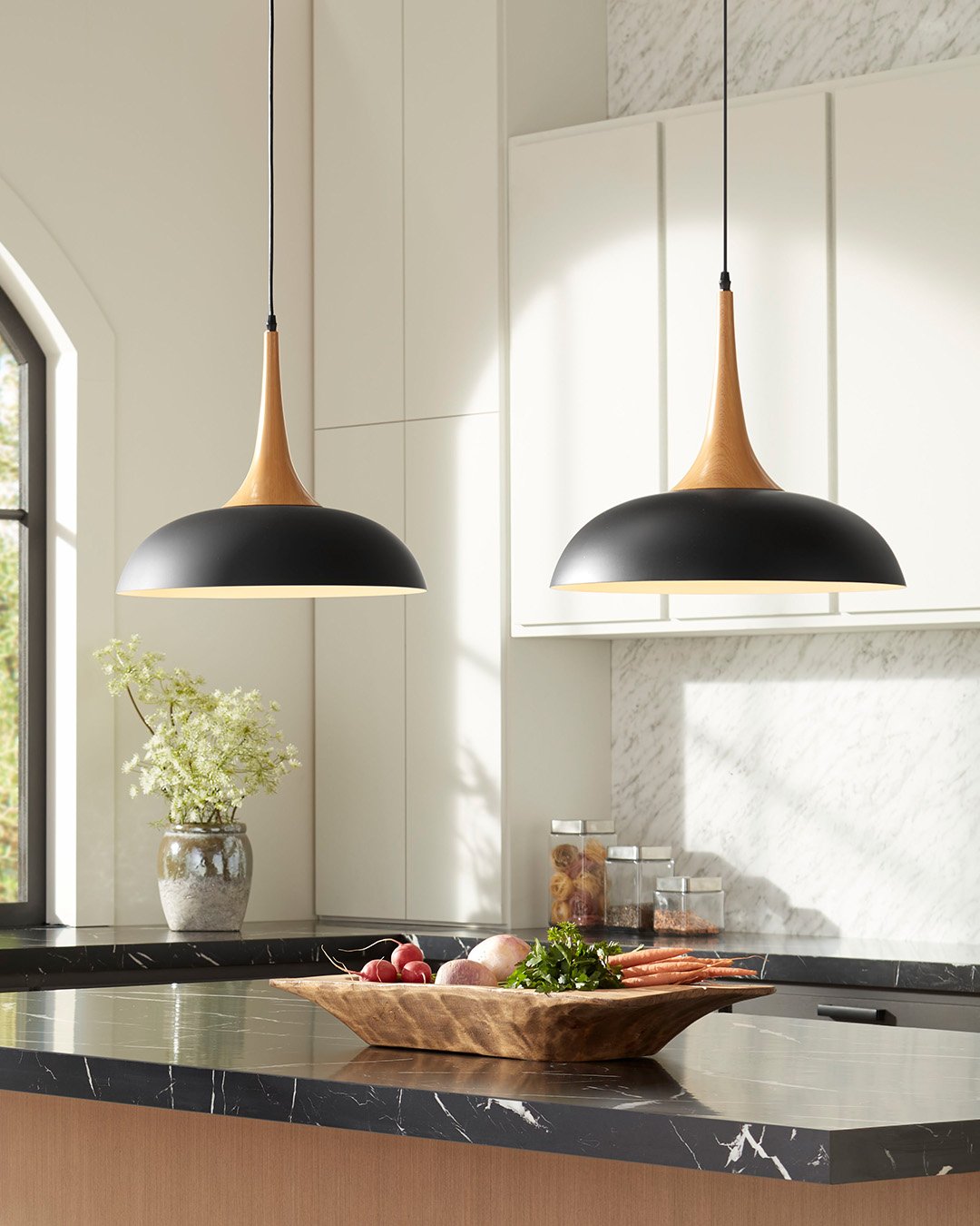 Two imposing metal conical pendants with a flat top over a white marble kitchen island.