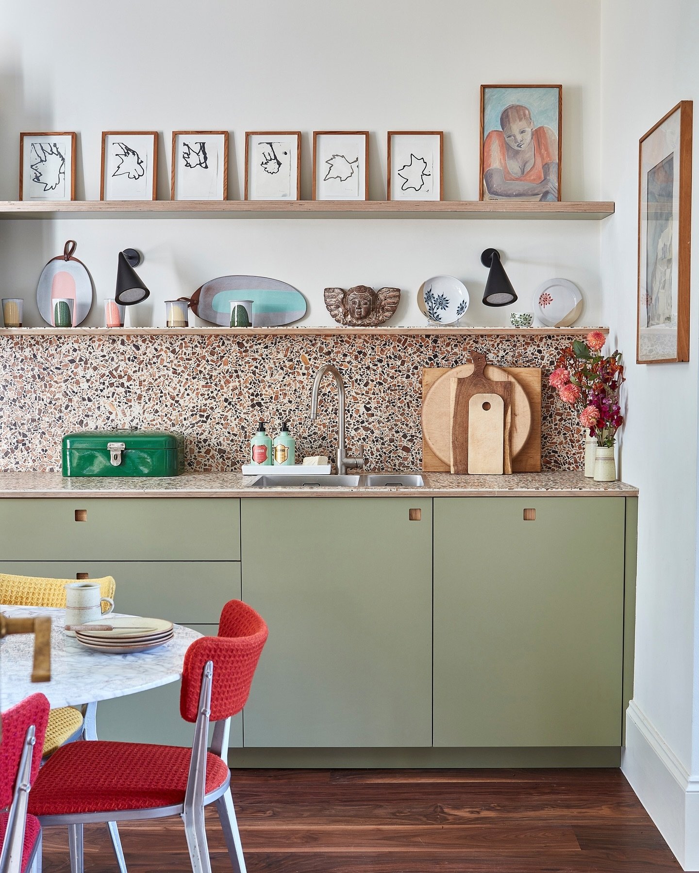 A large, multi-colored abstract artwork hanging above a built-in seating bench in a kitchen dining area.