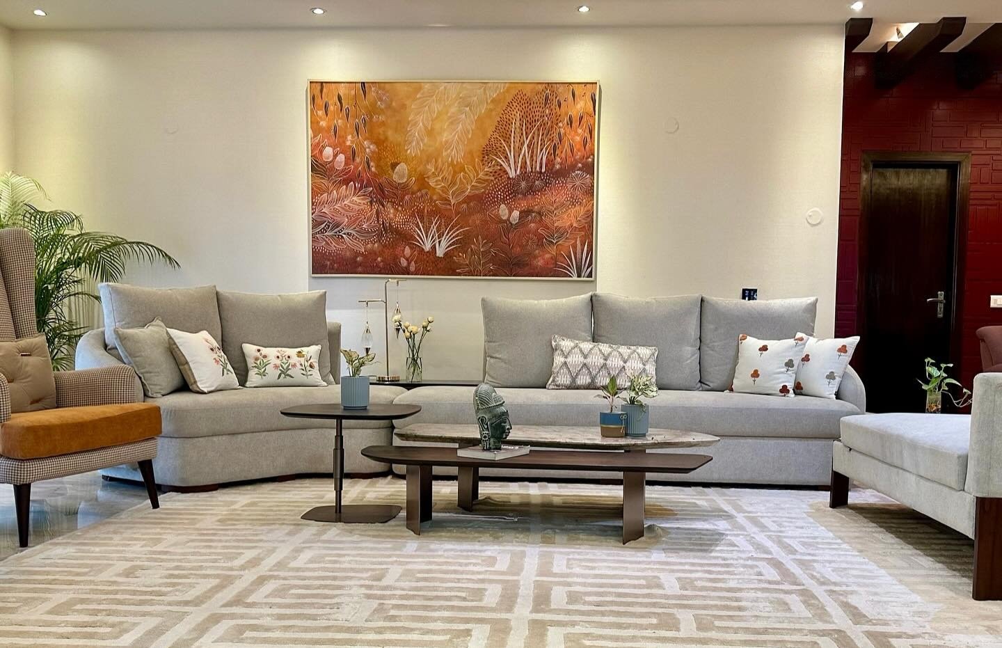 Living room with large light grey sofa, patterned beige rug, and striking abstract painting in shades of orange and brown.