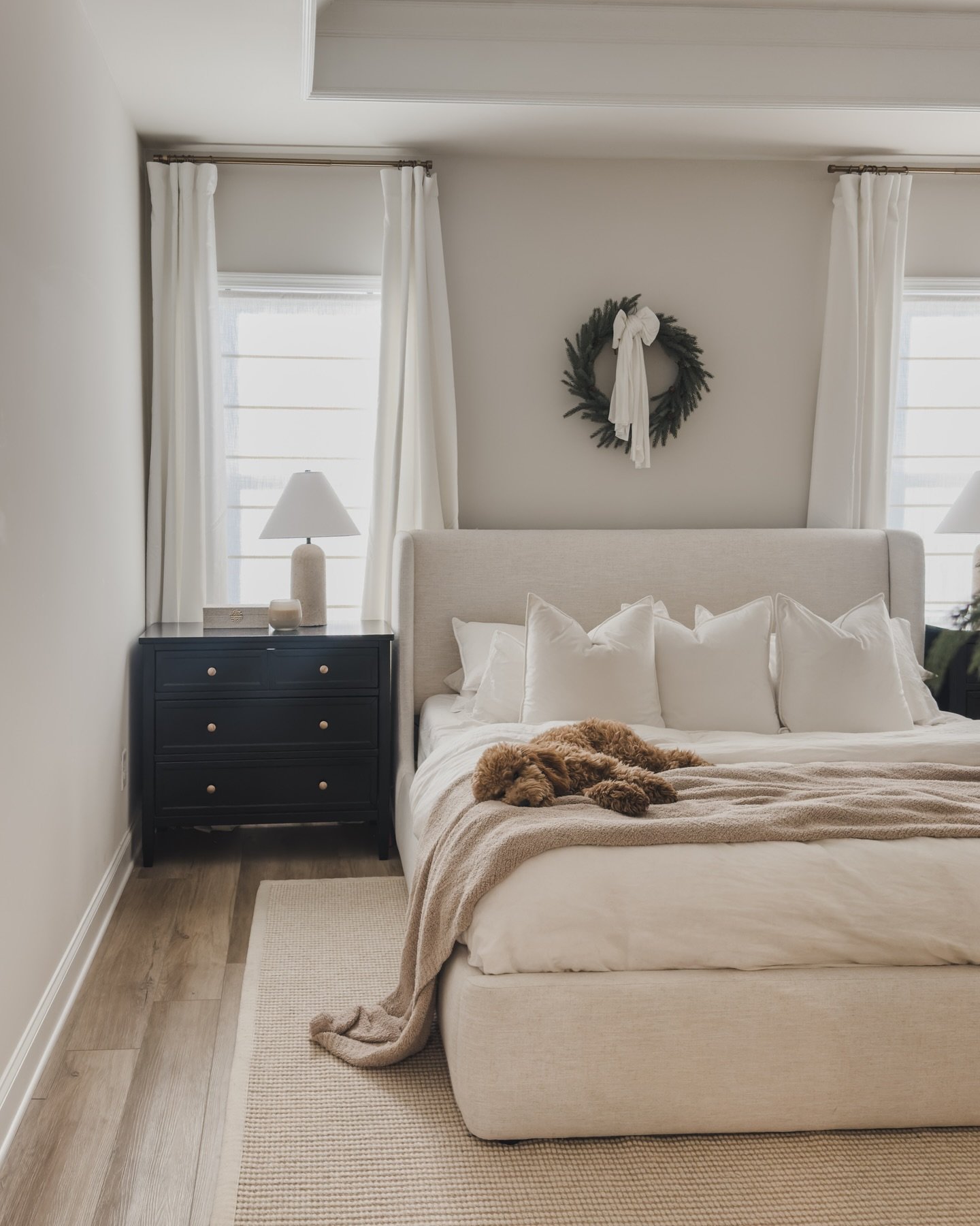 Pair of three-drawer black nightstands with small brass knobs flanking a black fluted headboard and bed frame.