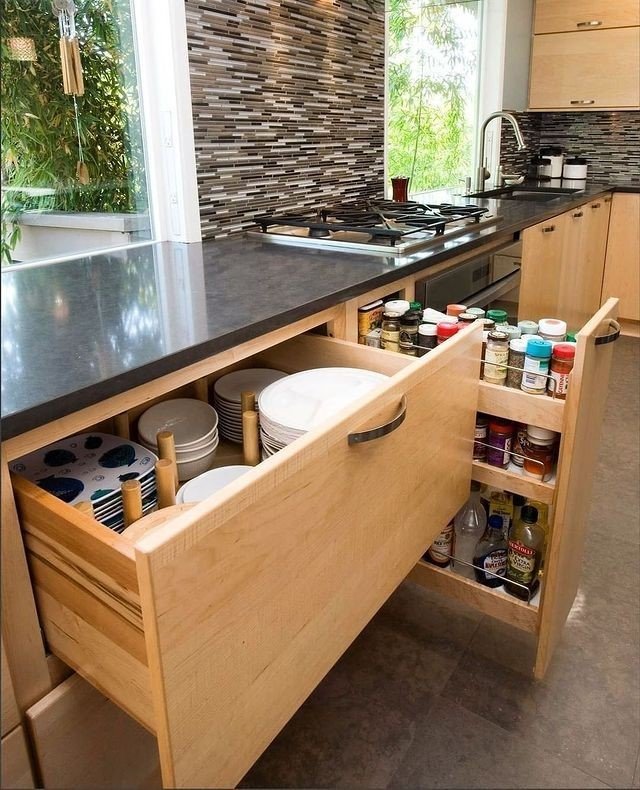 Light wood kitchen drawer with a custom section for stacking plates next to a vertical pull-out spice rack.