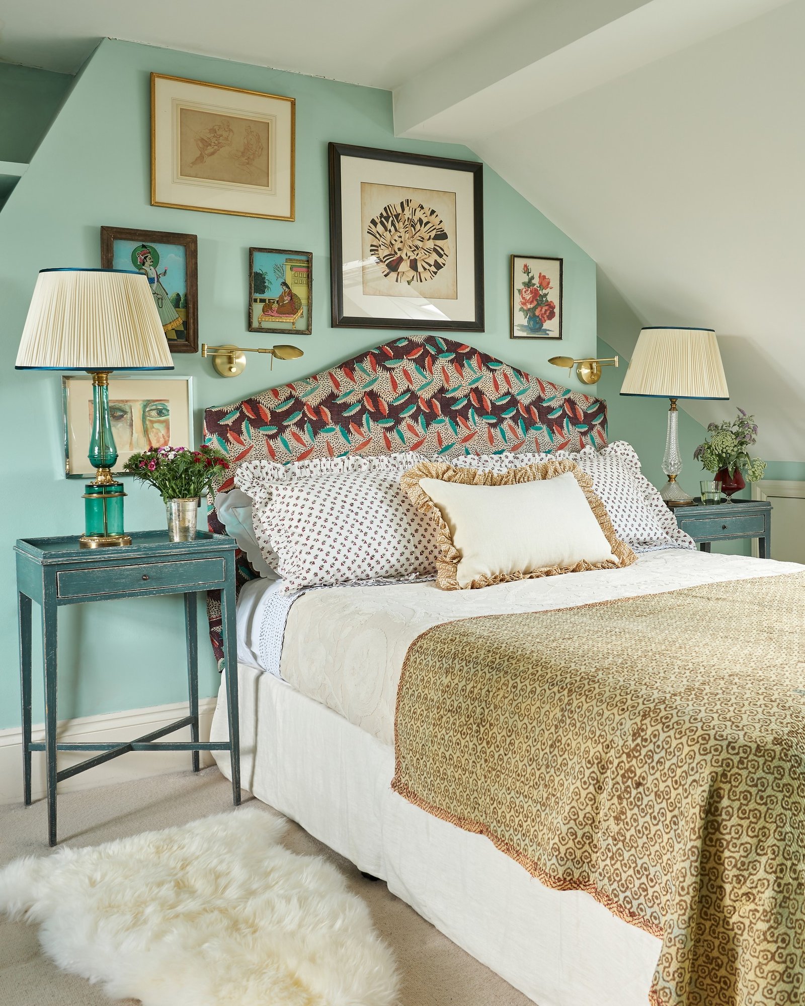 Medium-height headboard with a slightly arched top, upholstered in a highly colorful, botanical-patterned fabric set against a pale mint green wall.