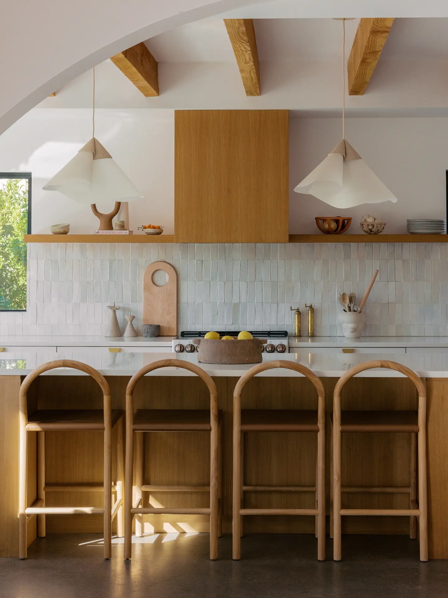 Unique handmade ceramic pendants in an organic, uneven shape over a neutral kitchen island.