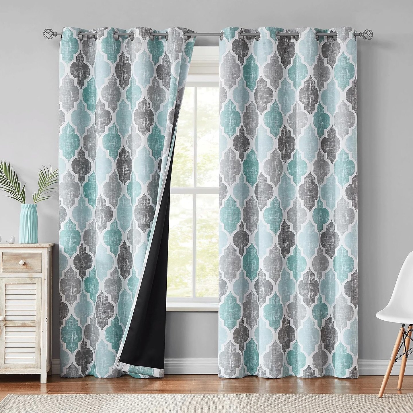Teal and gray geometric blackout curtains with grommet tops hanging on a window.