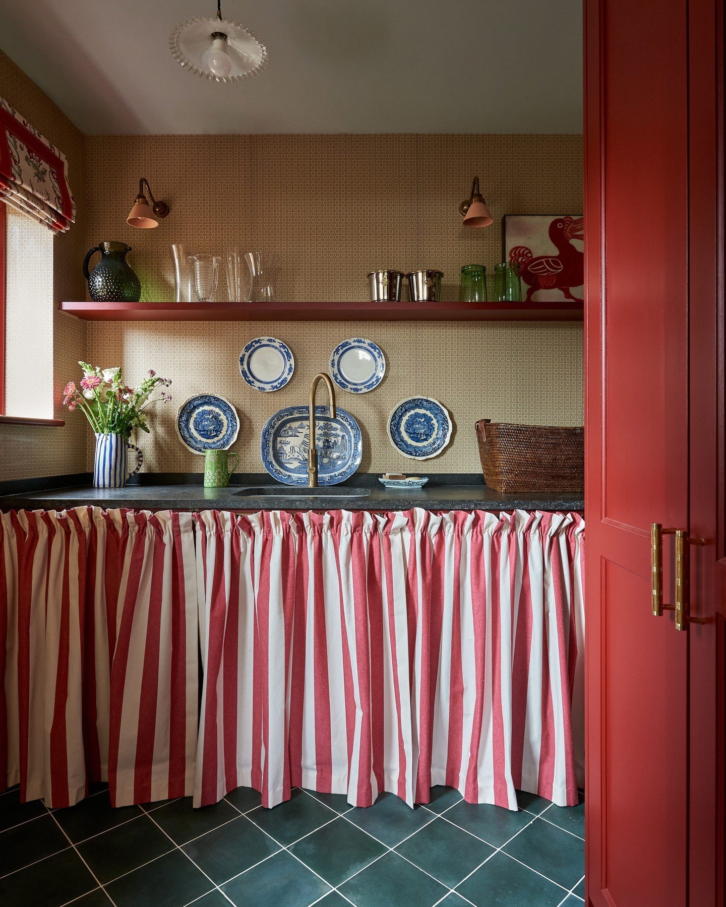 Laundry or utility room featuring a sink area with a gathered, floor-length fabric skirt in bold red and white vertical stripes beneath the counter.