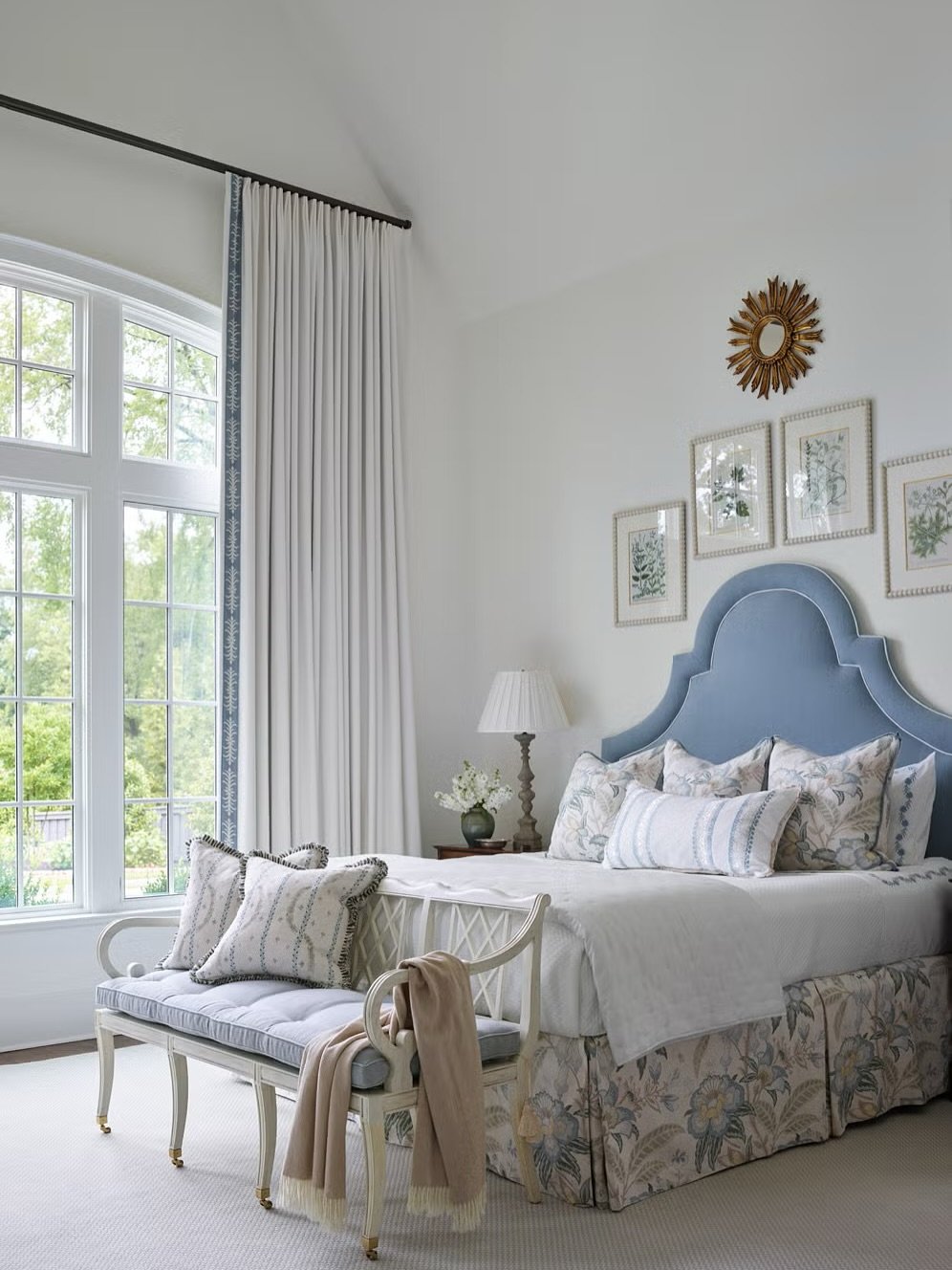 High, custom upholstered headboard in a pastel blue velvet with a classic camelback silhouette and light-colored contrast piping, in a traditional bedroom.
