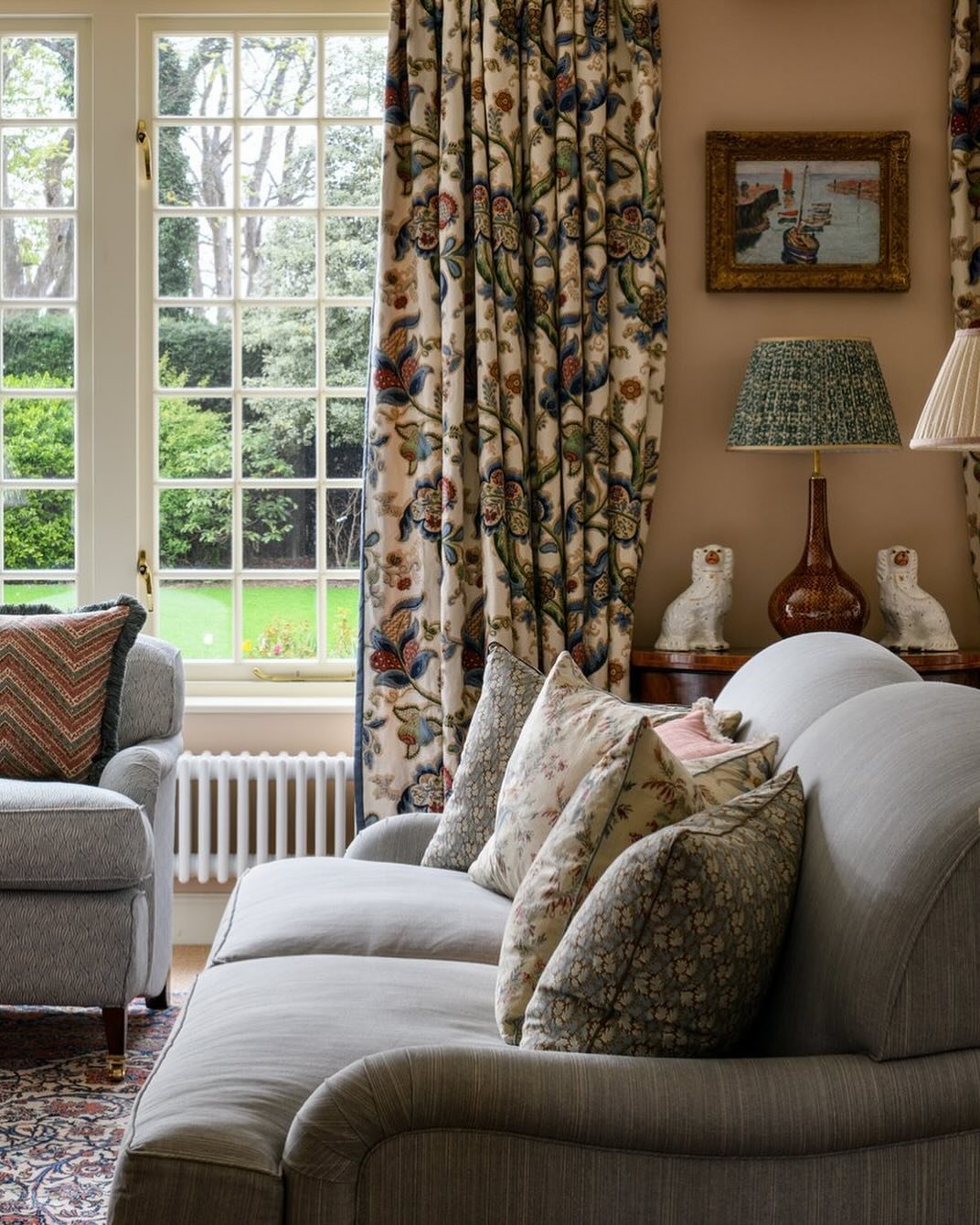 Custom-made curtains with a detailed, traditional floral pattern in deep colors, framing a window in a cozy living room.