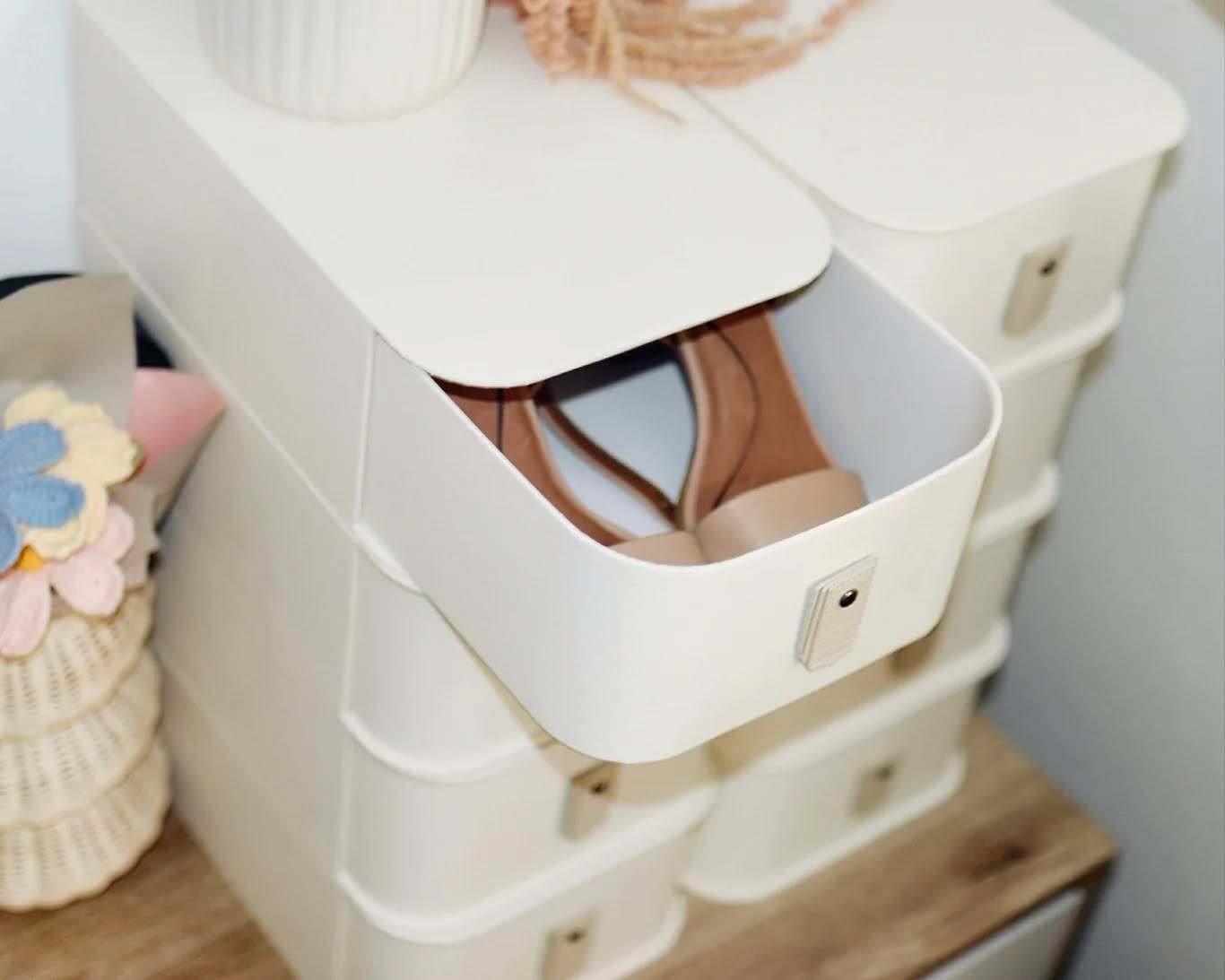 Stacked white plastic shoe storage boxes with a small front drawer pulled out, showing a pair of beige sandals.