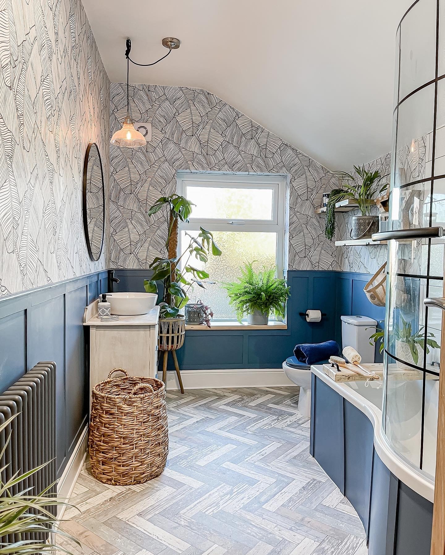 bright bathroom with deep blue wainscoting and a floor of weathered gray and white luxury vinyl plank (LVP) laid in a chevron pattern.