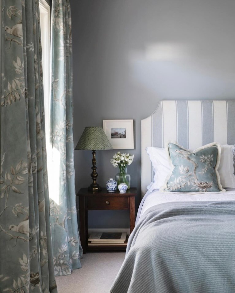 Dusty blue curtains with a delicate bird and branch pattern in a serene bedroom.