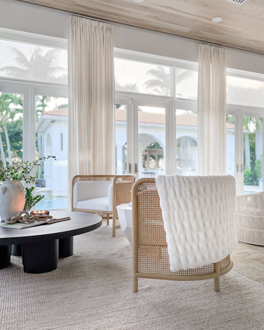 Very tall, light beige sheer curtains framing expansive floor-to-ceiling glass doors in a modern, airy living room.