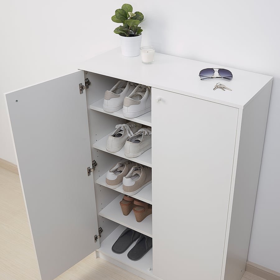 Small white cabinet with five internal shelves, one door open revealing neatly stored pairs of casual shoes.