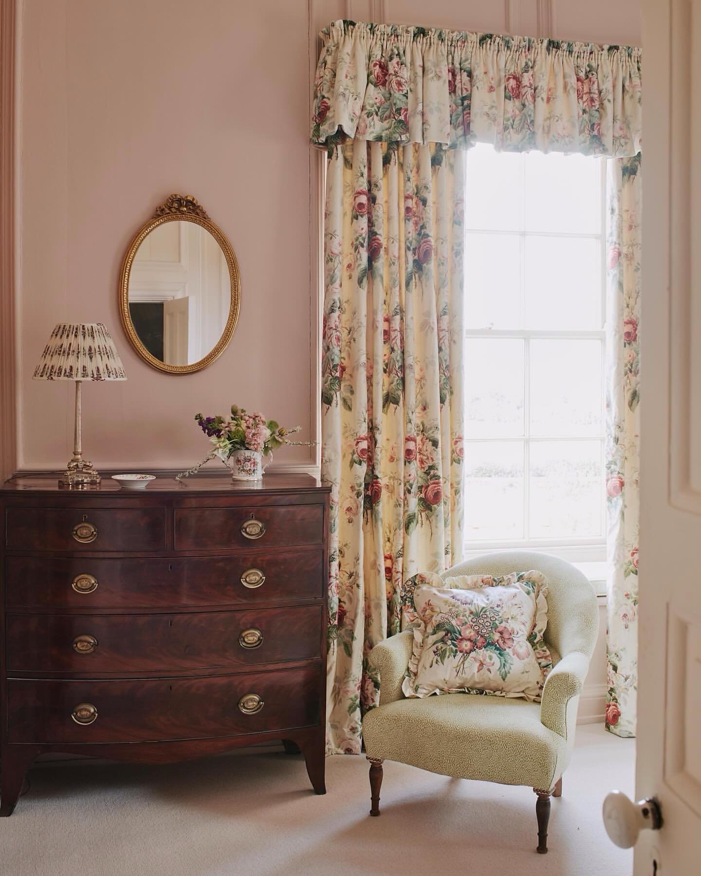 Traditional floral chintz curtains with a matching valance in a pink-walled room.