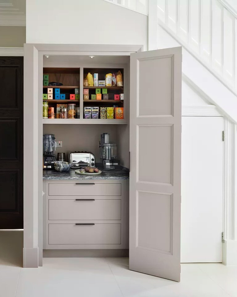 Under-stairs closet with a counter for small kitchen appliances and shelving for food items.