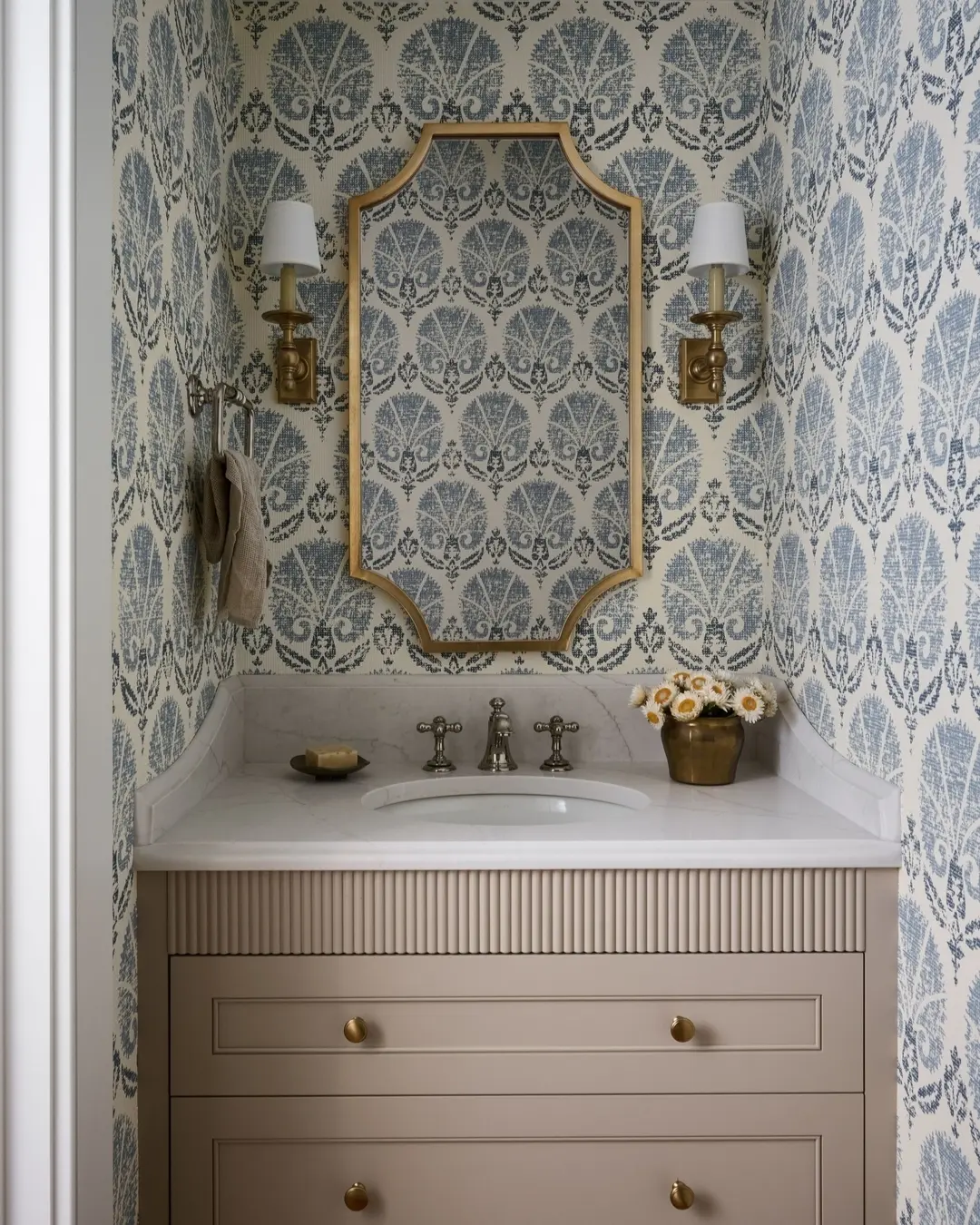 Neutral vanity with blue and white patterned damask wallpaper.