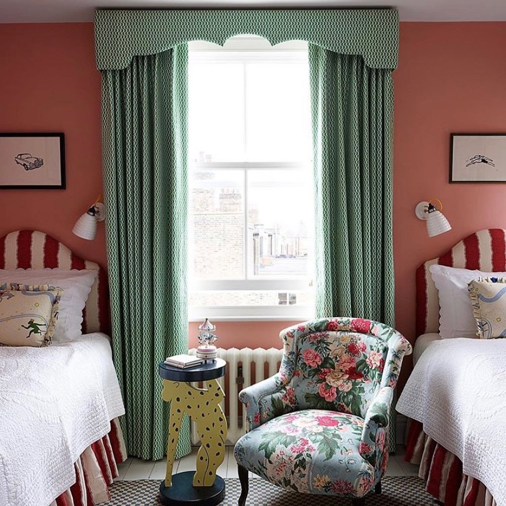 Bold green patterned curtains with a scalloped valance in a maximalist pink and red bedroom.