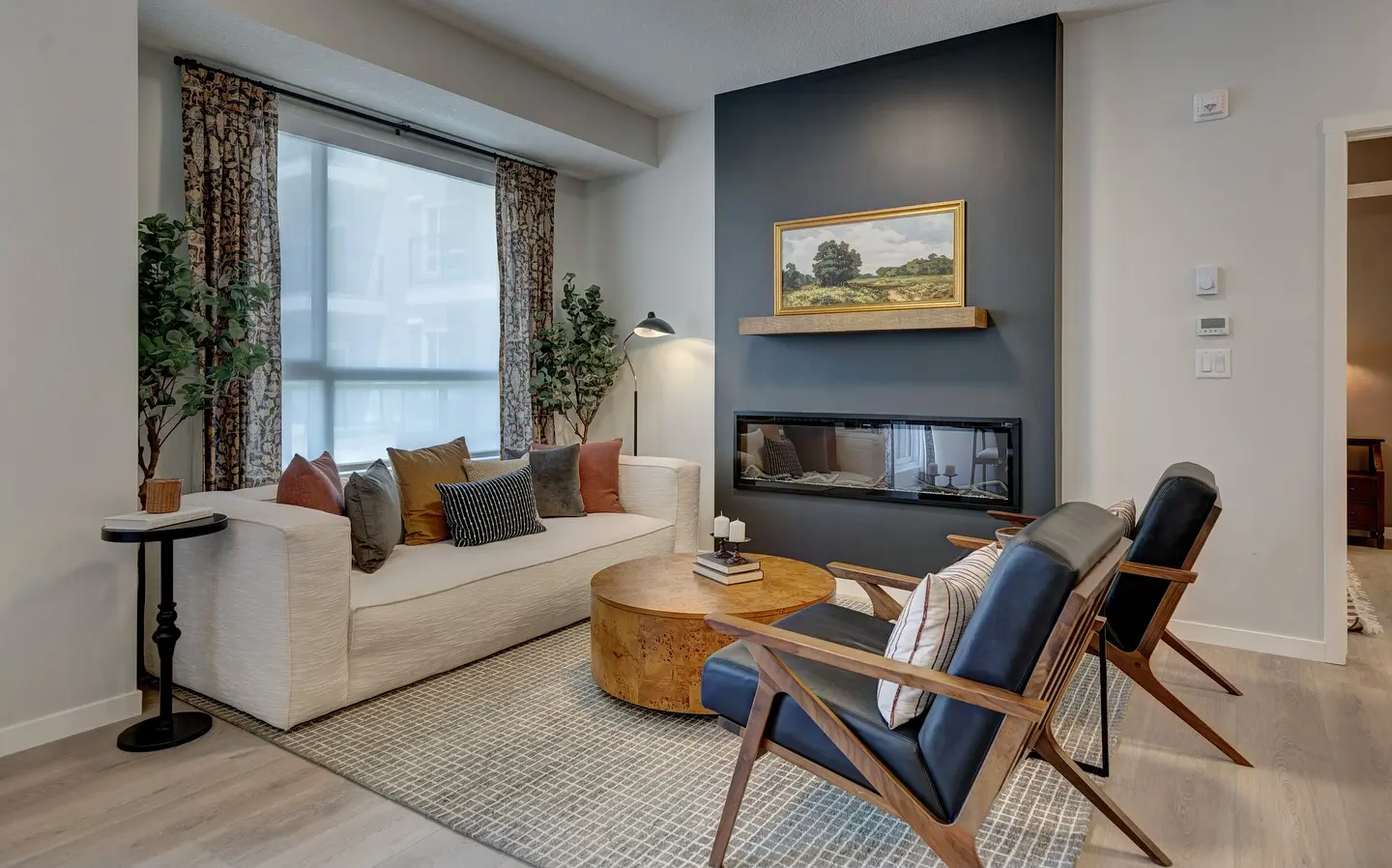 Wide, black linear electric fireplace recessed into a slanted dark gray accent wall above a floating wood mantel shelf, in a modern living room.