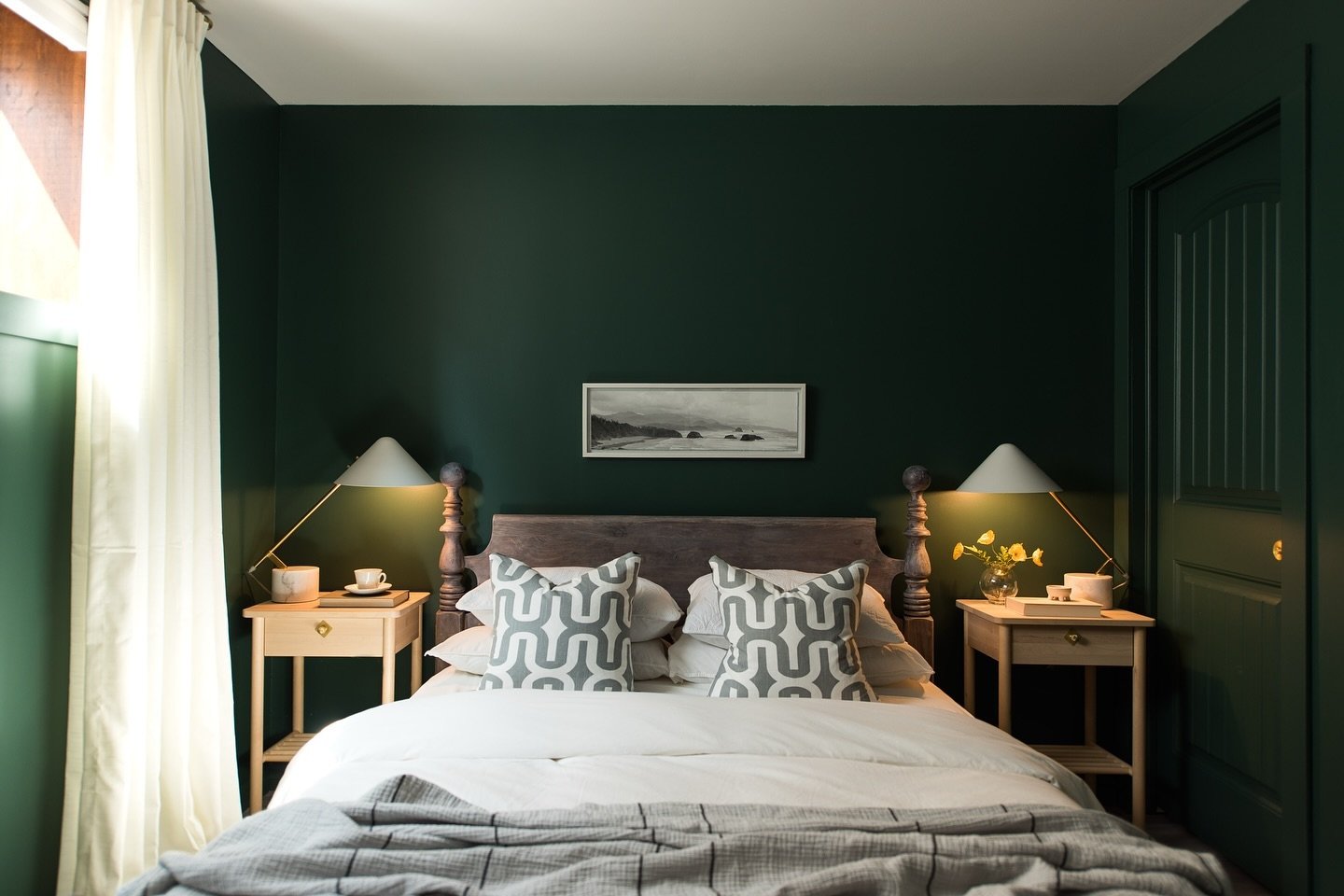 Bedroom with a solid, deep forest green wall, a rustic wooden spindle bed, and matching light wood nightstands.