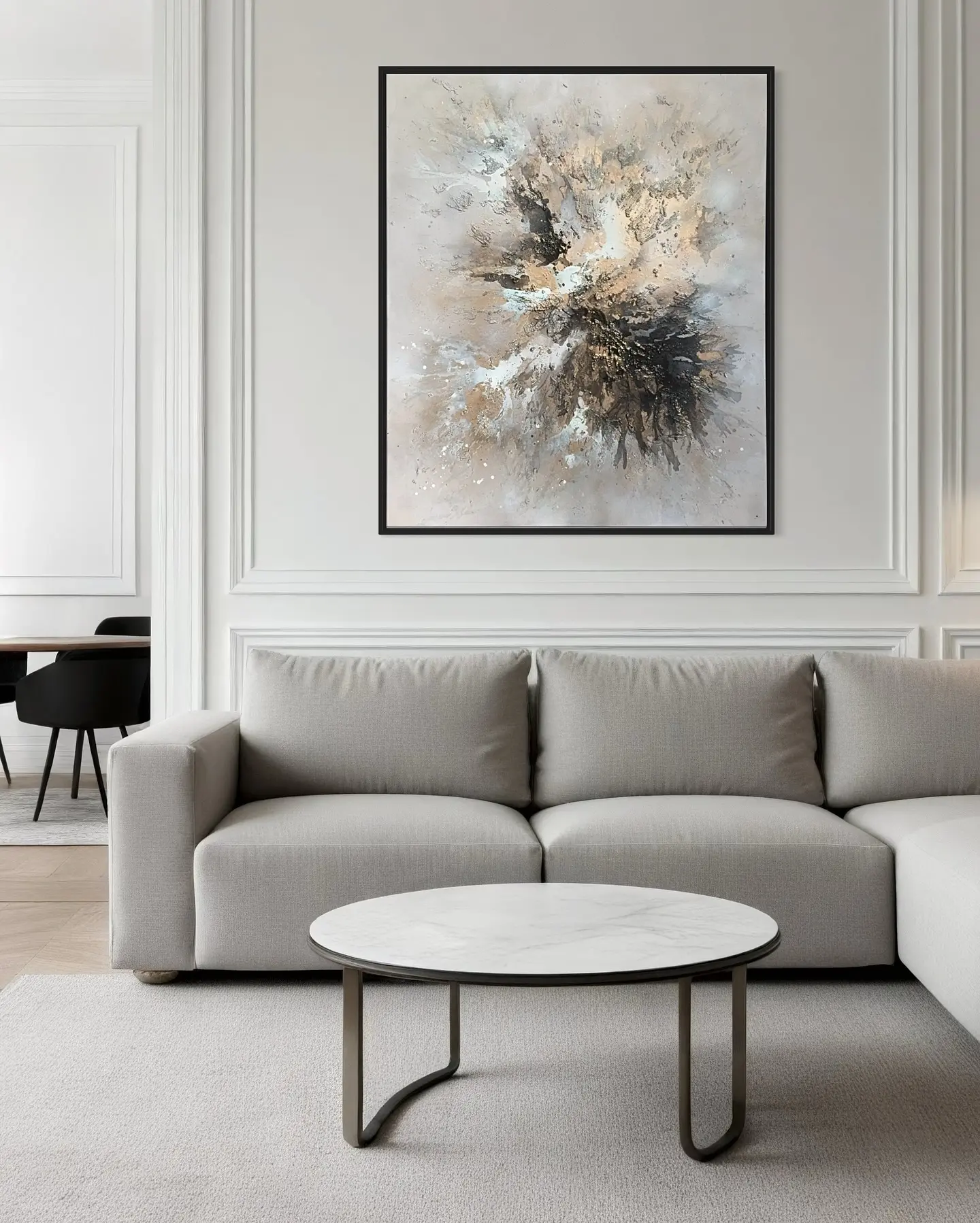 Large vertical abstract painting in black, white, and gold splatter patterns, framed in black and hung above a light grey sofa.