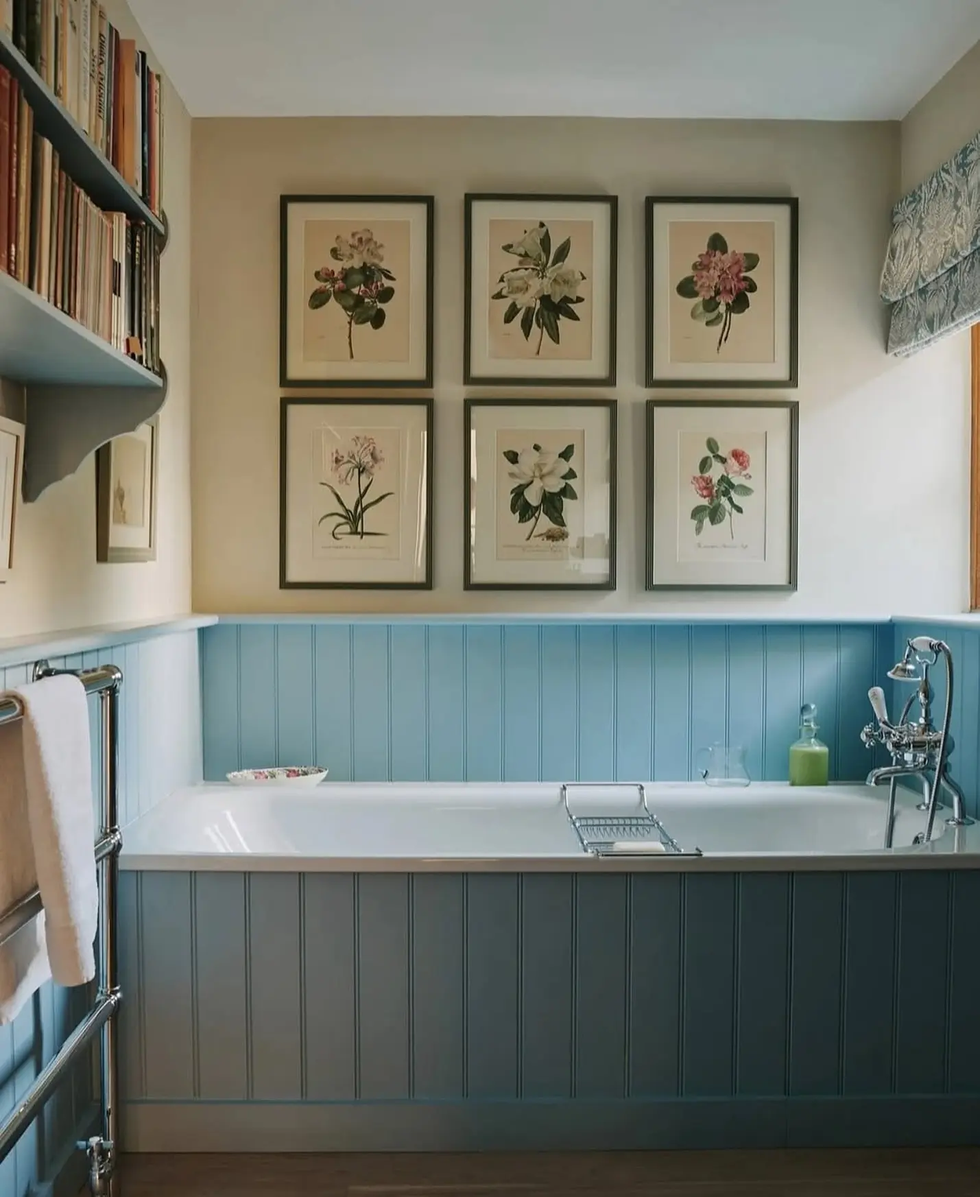 A cozy bathroom with blue wainscoting and a built-in tub, featuring a grid of six framed, dark-framed antique botanical flower prints.