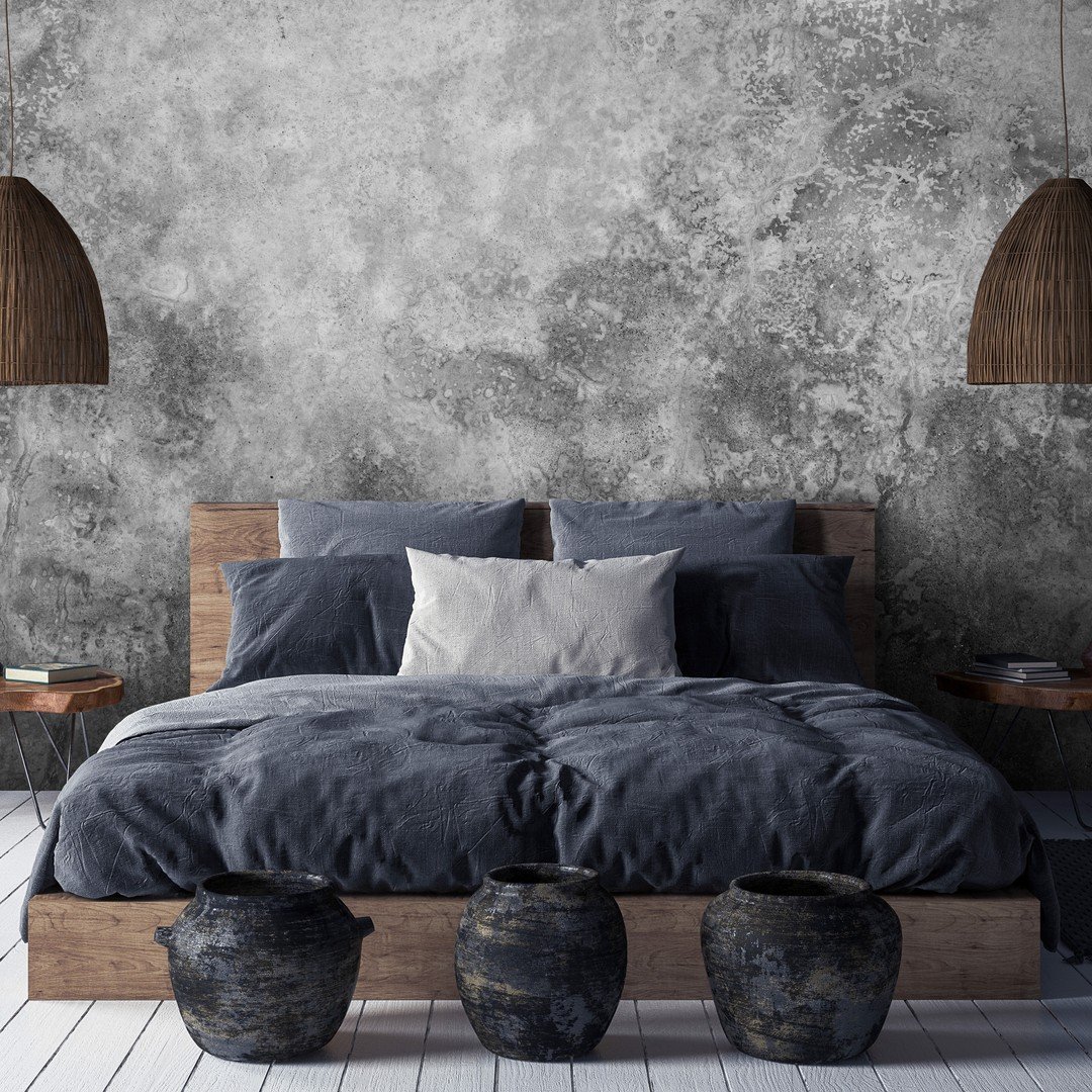 Dark bedroom with a highly textured, aged concrete or plaster effect wall, a low natural wood bed frame, slate blue bedding, and large woven pendant lights.
