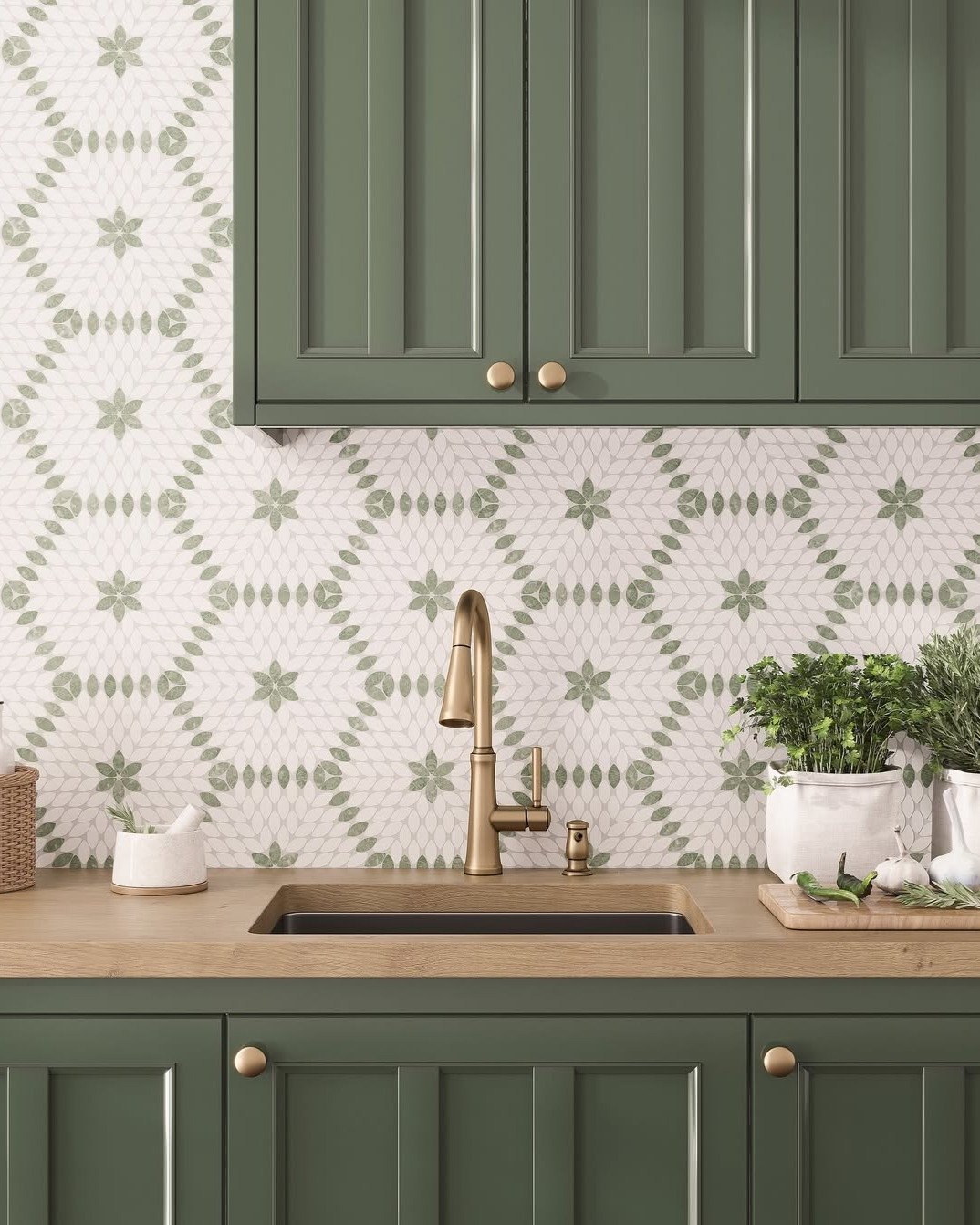 Kitchen backsplash with a repeating floral and diamond pattern in soft sage green and white, complemented by dark green shaker cabinets and a brass faucet.