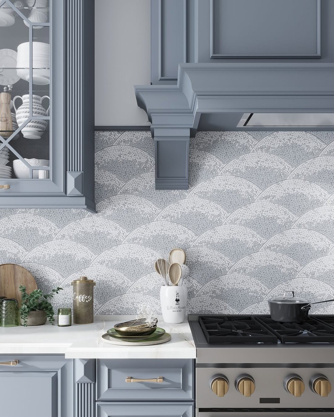 Kitchen backsplash featuring a wide scallop or fish scale pattern rendered in a textured white and light blue mosaic, paired with slate blue cabinetry and gold hardware.